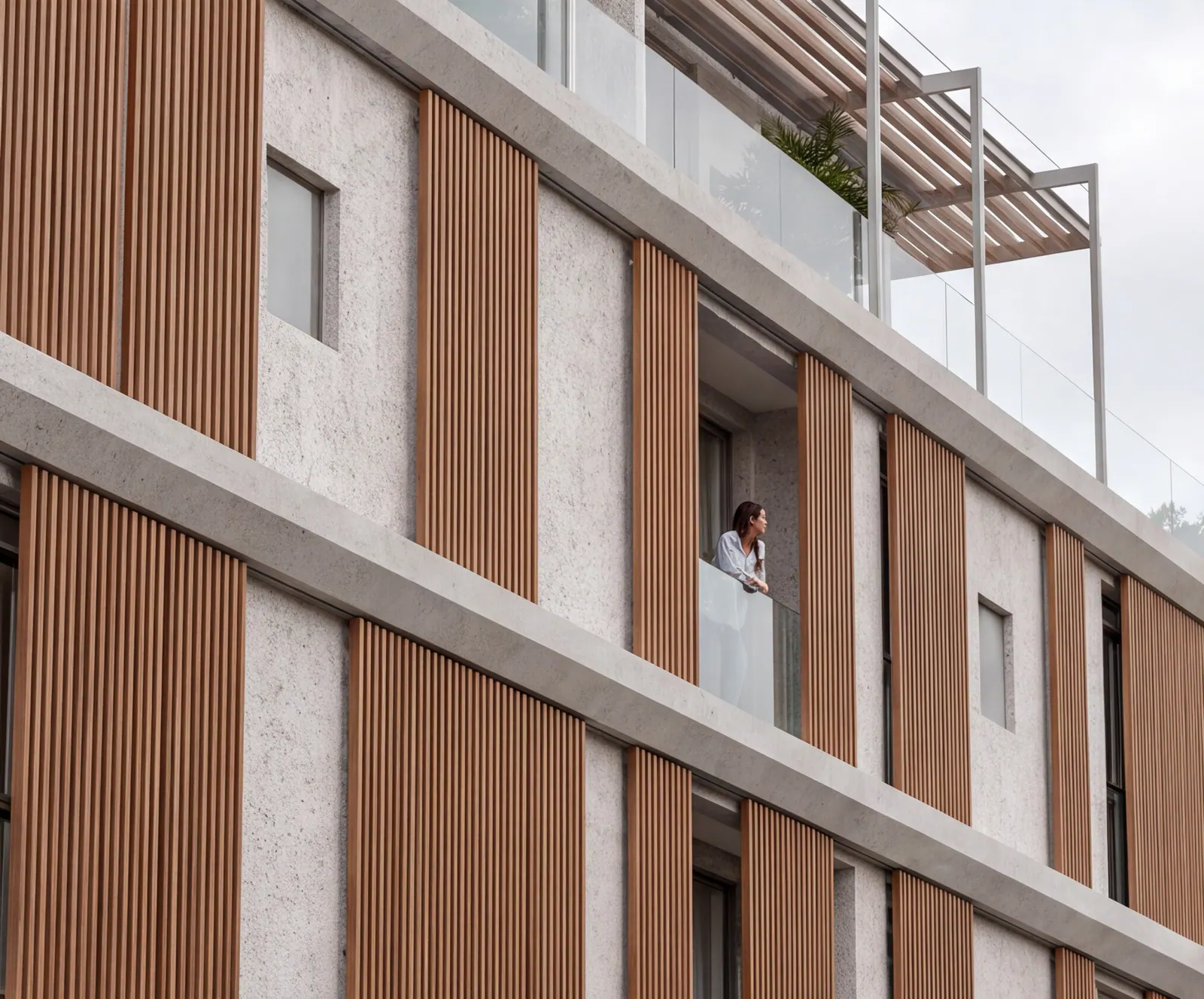A resident at an open window between the timber louvres