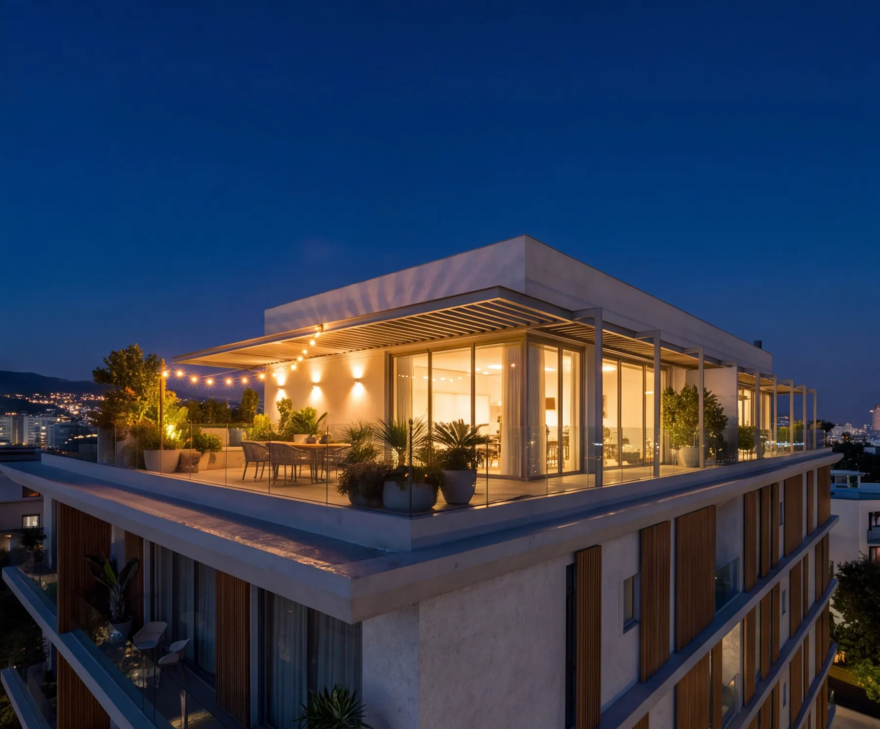 The penthouse roof terrace lit at night above the city